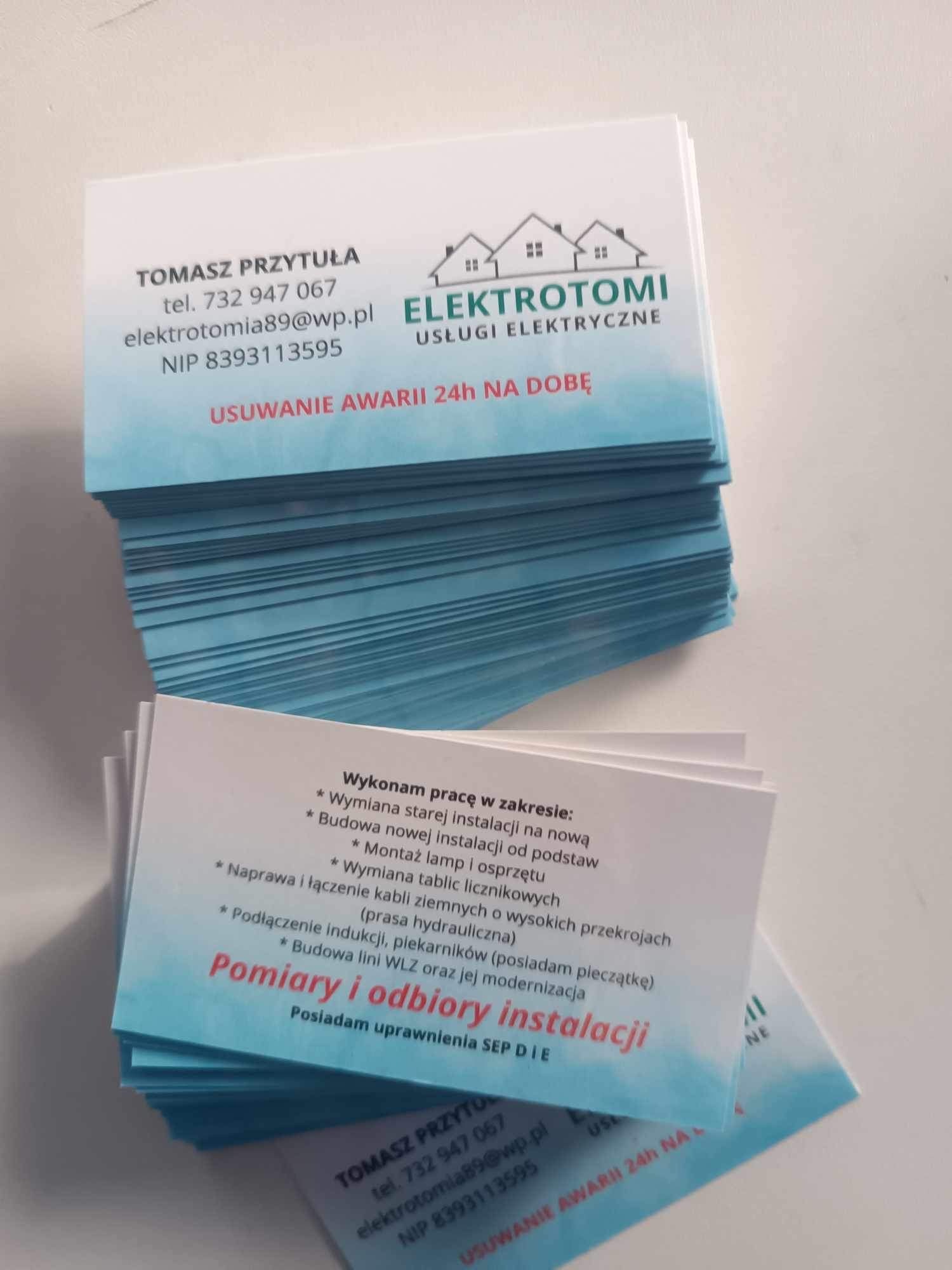 Stos wizytówek firmy Elektrotomi świadczącej usługi elektryczne, z informacjami kontaktowymi i zakresem usług, w tym usuwanie awarii 24h, pomiary i odbiory instalacji.