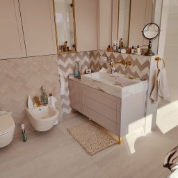 Lukasz Fabisiak - Jasna łazienka z szafką pod umywalkę z marmurowym blatem, bidetem i lustrami. Uwagę przykuwają złote detale: armatura, uchwyt na ręcznik i nóżki szafki.