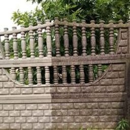 T&M Malowanie Dachów I Elewacji. - Fragment ogrodzenia z betonu architektonicznego, z wyraźną różnicą między czystą, jasną częścią po lewej i brudną, ciemną częścią po prawej stronie, ukazując efekt przed i po czyszczeniu...