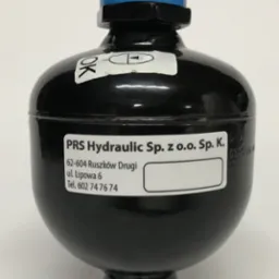 Czarny akumulator hydrauliczny z niebieską g&oacute;rną częścią, oznaczony etykietą z adresem firmy PRS Hydraulic Sp. z o.o. Sp. K.