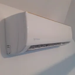 Biała jednostka klimatyzacji Rotenso, zamontowana na jasnej ścianie, z delikatnym złotym akcentem na górnej krawędzi.