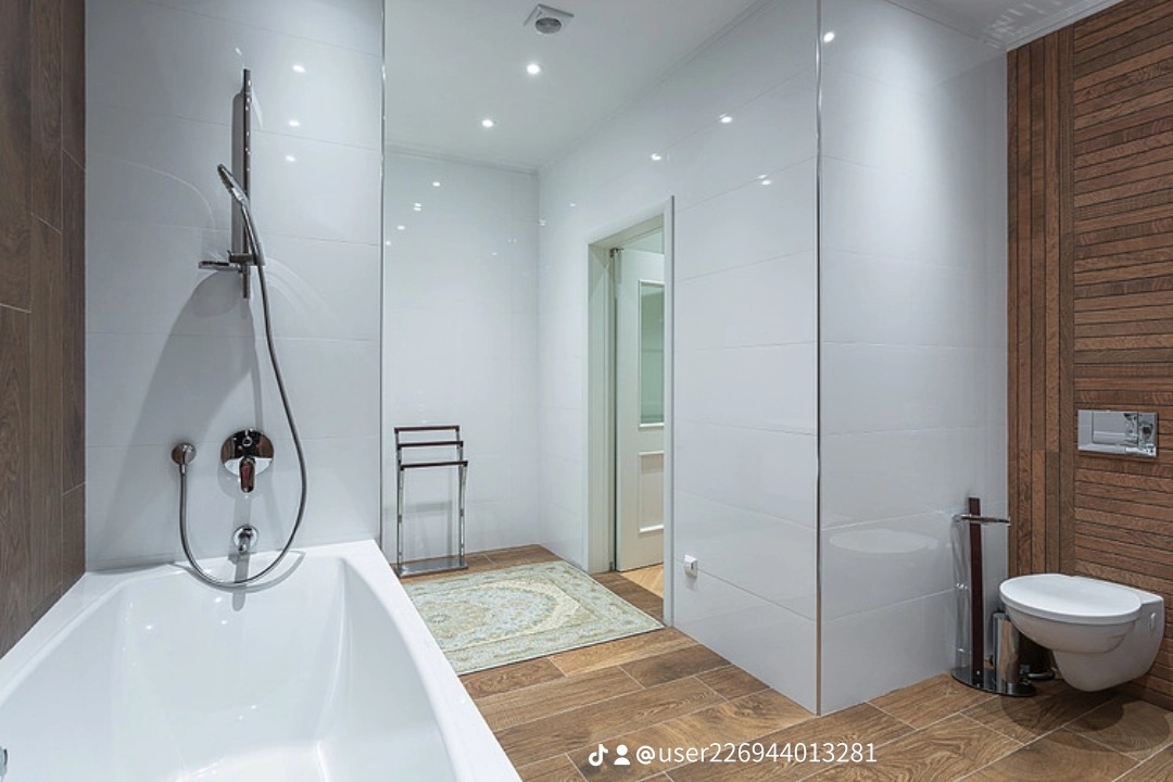 Nowoczesna łazienka z białymi płytkami, drewnianymi akcentami i minimalistycznym wyposażeniem, w tym wiszącą toaletą i chromowaną armaturą.