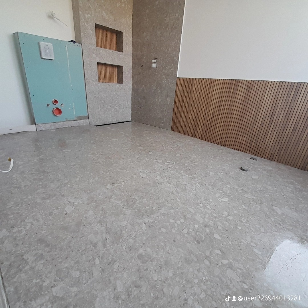 Wnętrze łazienki w trakcie wykańczania, widoczna zabudowa ściany z półkami, płyty gipsowe przygotowane pod instalację sanitarną oraz drewniana boazeria na ścianie, posadzka wyłożona płytkami...