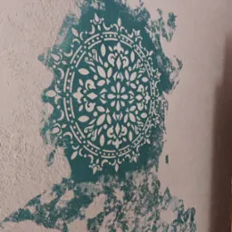 Teksturowana ściana z dekoracyjnym, turkusowym wzorem mandali. Biały ornament na nierównej powierzchni. Efektowna dekoracja wnętrza w zbliżeniu.