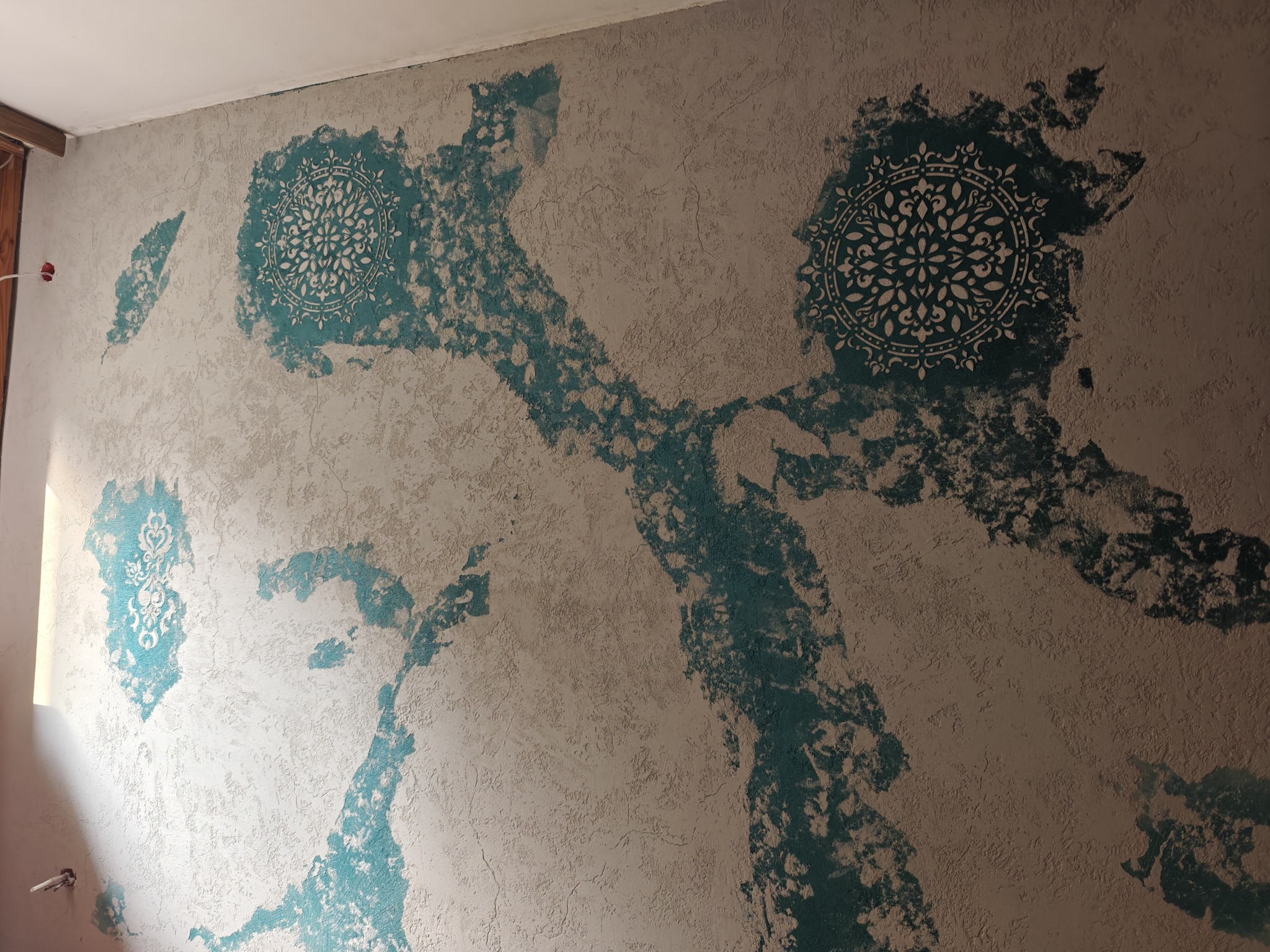 Dekoracyjna ściana z beżową fakturą i turkusowymi wzorami mandali. Unikalny efekt artystyczny na ścianie, wykonany techniką malarską.