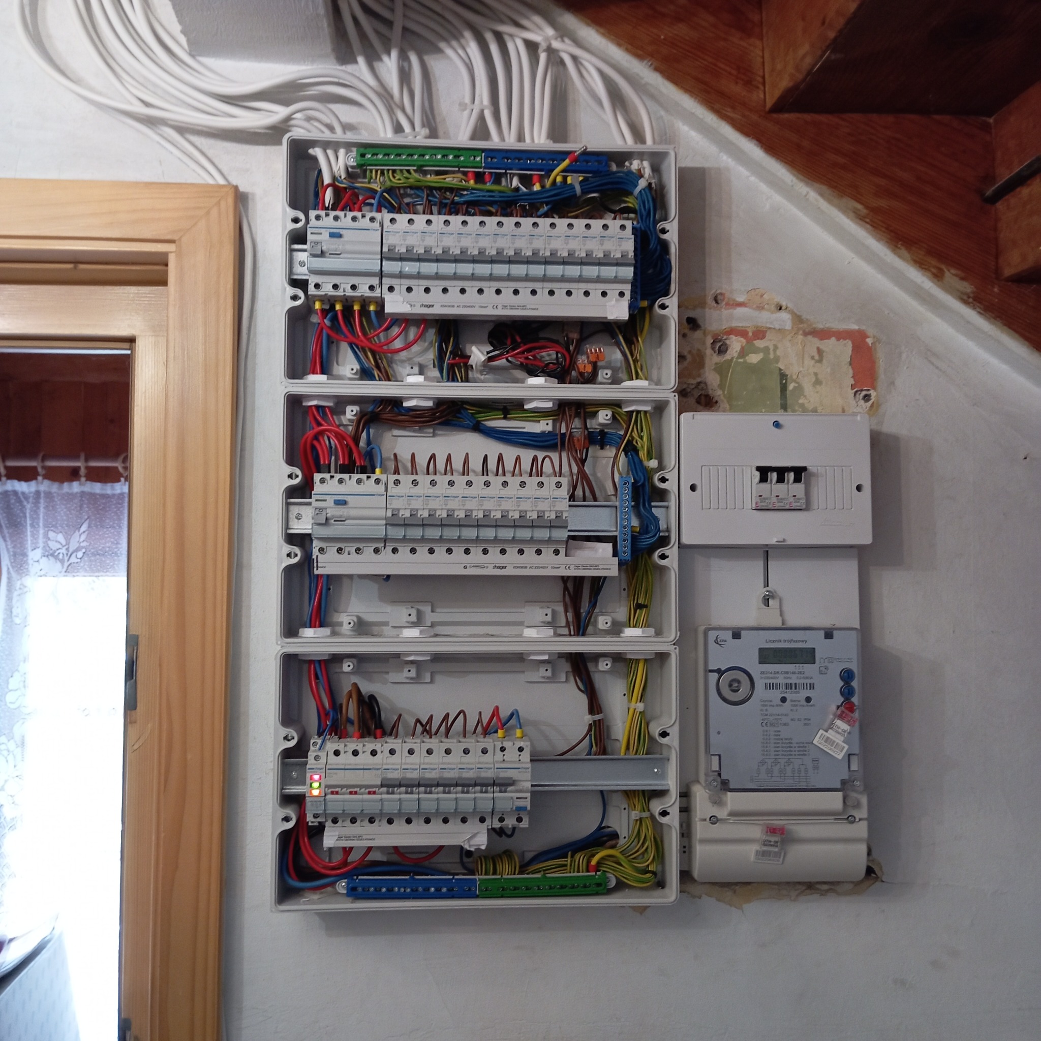 Rozdzielnia elektryczna w domu jednorodzinnym, widok z bliska na zamontowane bezpieczniki, kable i licznik energii. Nowa instalacja, po zakończeniu prac.