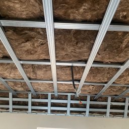 Konrad Sobol - Montaż wełny mineralnej w metalowym ruszcie sufitu podwieszanego z płyty karton gips, widoczne przewody elektryczne