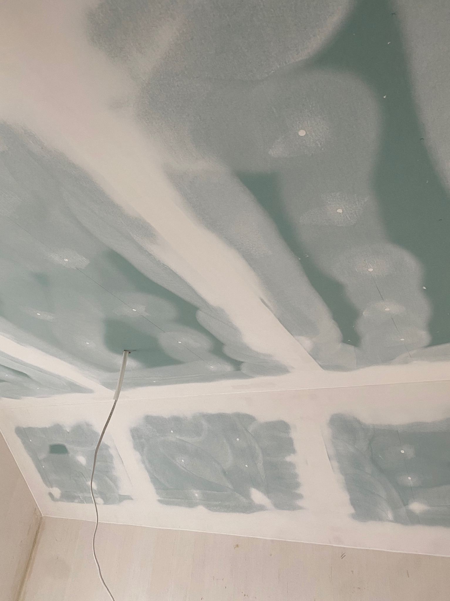 Sufit z płyt kartonowo-gipsowych, częściowo wyszpachlowany, widoczne łączenia i szpachlowane wkręty, przewód elektryczny zwisający z sufitu.