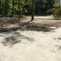 Aldis STANISŁAW GRYGORIEW - Ścieżka parkowa z jasnej nawierzchni mineralnej, obrzeża z kostki granitowej, cień drzew na podłożu.