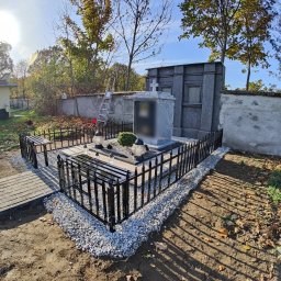 Artystal Paweł Krzan - Metalowe ogrodzenie z ławkami otaczające nagrobek na cmentarzu, z drobnymi kamieniami i płytami chodnikowymi.