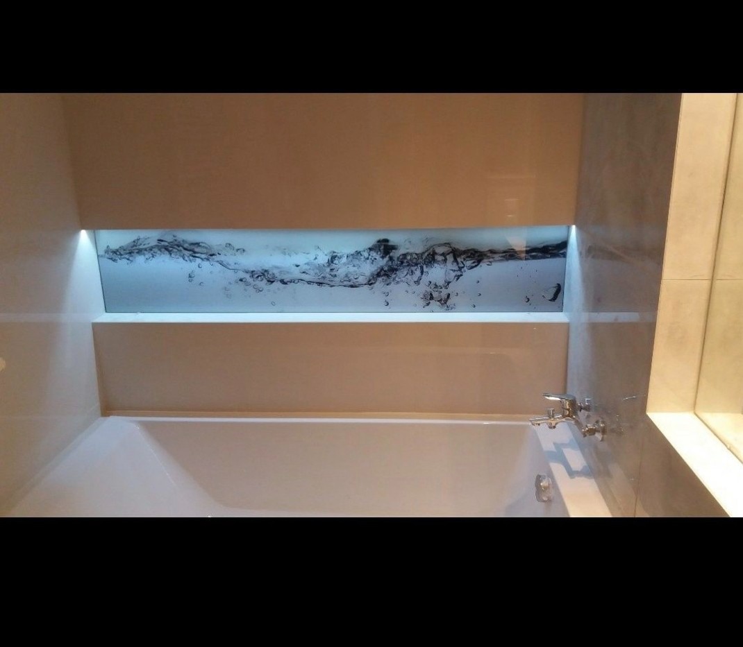 Podświetlany panel szklany z motywem wody nad wanną w łazience, widoczne chromowane krany.