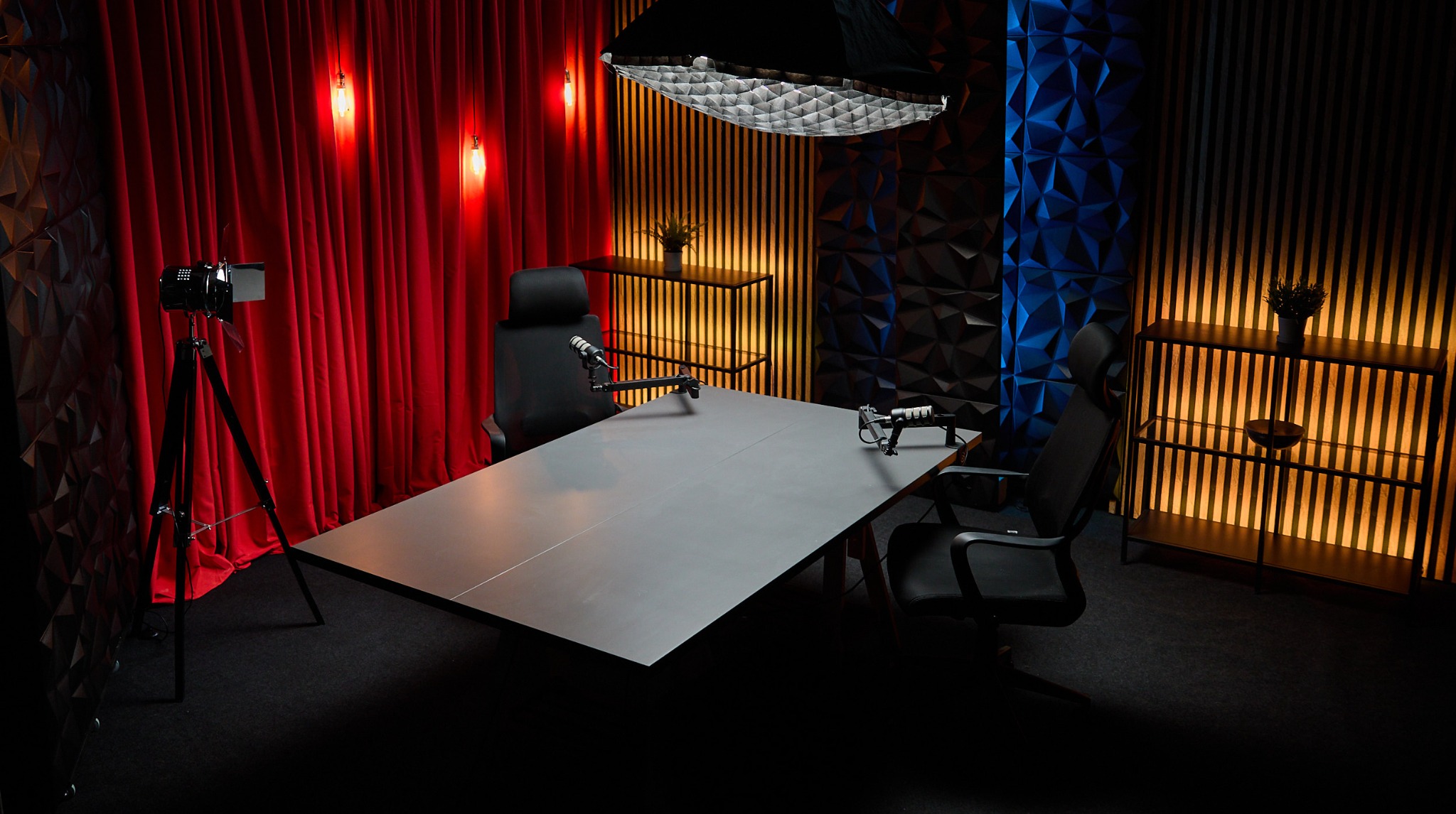Profesjonalne studio nagrań z mikrofonami, oświetleniem i dekoracyjnymi ścianami w odcieniach czerwieni, złota i błękitu, gotowe do realizacji nagrań wideo.