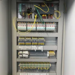 Otwarta szafa sterownicza z modułami, okablowaniem i oznaczeniami, widoczne elementy Siemens,  układ zasilania SITOP.