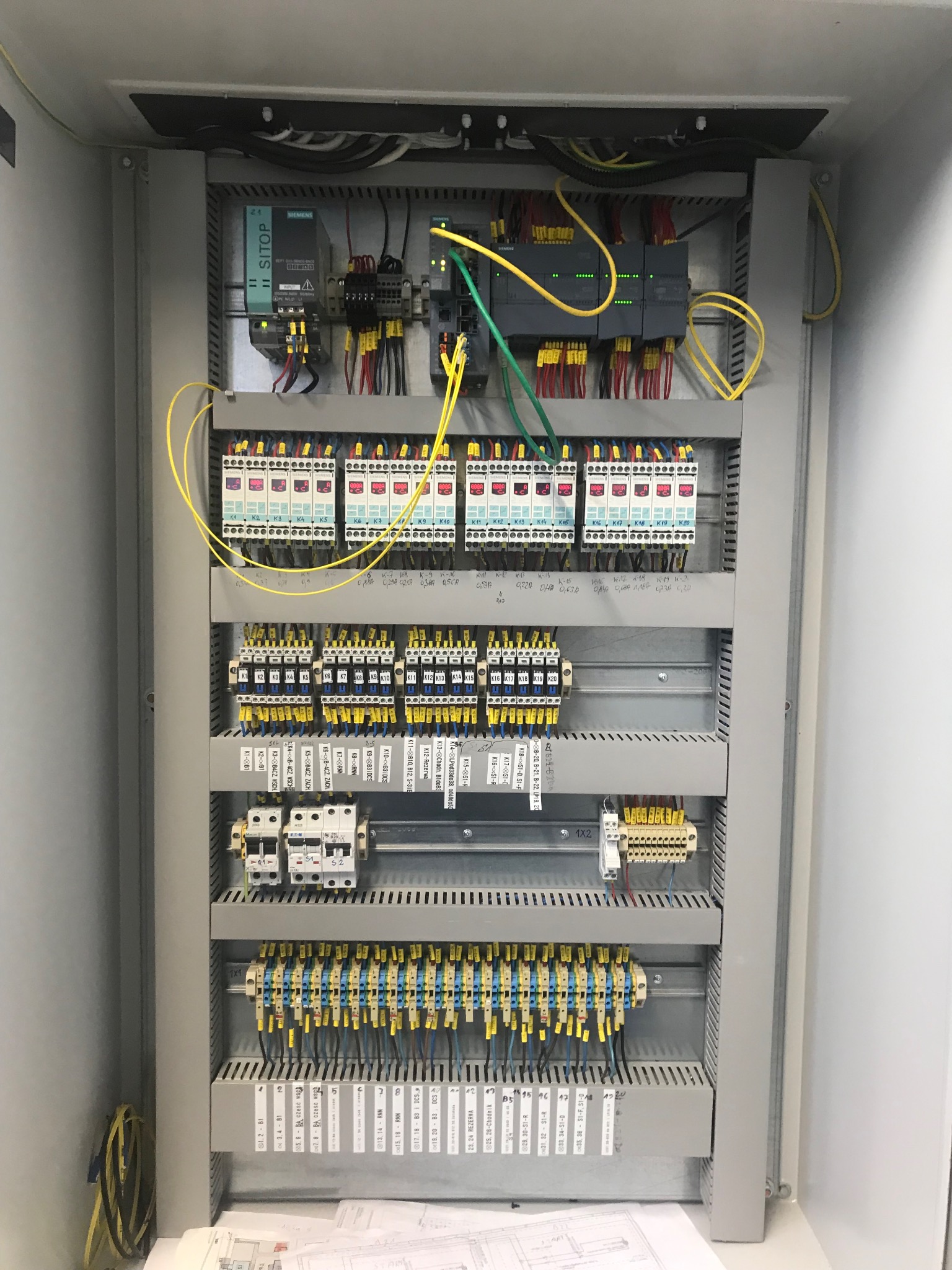 Otwarta szafa sterownicza z modułami, okablowaniem i oznaczeniami, widoczne elementy Siemens,  układ zasilania SITOP.