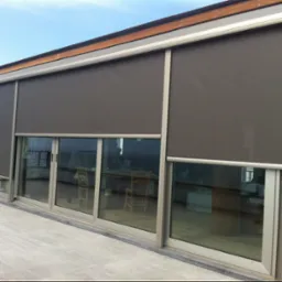 Zewnętrzne rolety w kolorze antracytowym na przesuwanych oknach balkonowych z aluminiowymi ramami, widok z zewnątrz, częściowo zasłonięte.