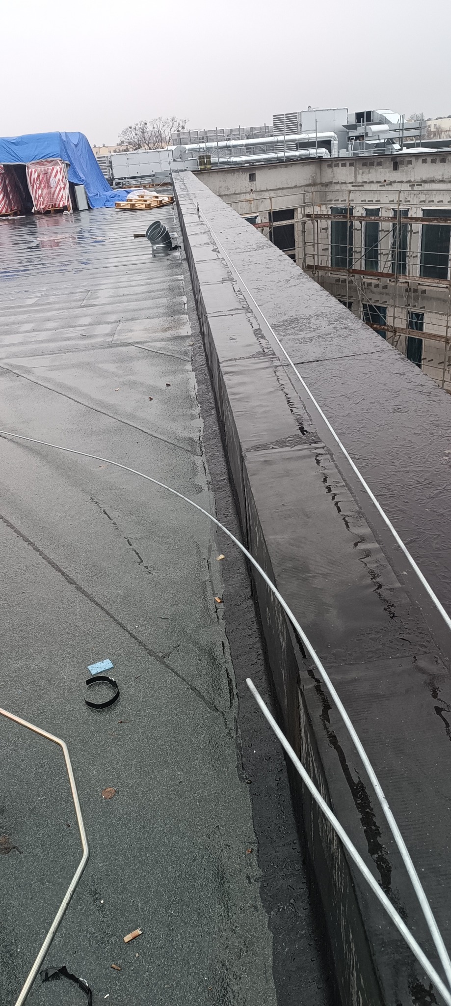 Montaż instalacji odgromowej na dachu budynku w Toruniu, widoczne przewody odprowadzające i elementy mocujące, w tle budynek w trakcie budowy.