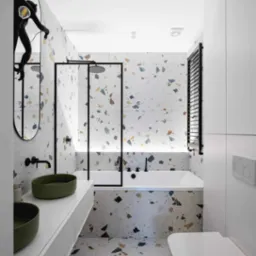 Nowoczesna łazienka z wanną, kabiną prysznicową typu walk-in, umywalkami nablatowymi w kolorze oliwkowym i wzorzystymi płytkami lastryko na ścianach i podłodze, uzupełniona czarnymi akcentami...