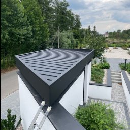 Dąb dach Paweł Dubicki - Nowoczesny dach z blachy trapezowej w kolorze antracytowym, widok z góry, Białystok. Minimalistyczny design, drabina oparta o ścianę, otoczenie zieleni.