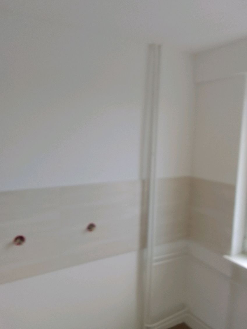 Przygotowana ściana z dwoma otworami na instalację elektryczną, widoczna listwa przypodłogowa i fragment okna.