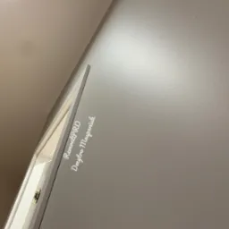 Świeżo pomalowana ściana w odcieniach szarości, widoczny fragment sufitu i ramy obrazu z zawieszką, na ścianie delikatny napis 'RemontPRO Dmytro Mospaniuk'.