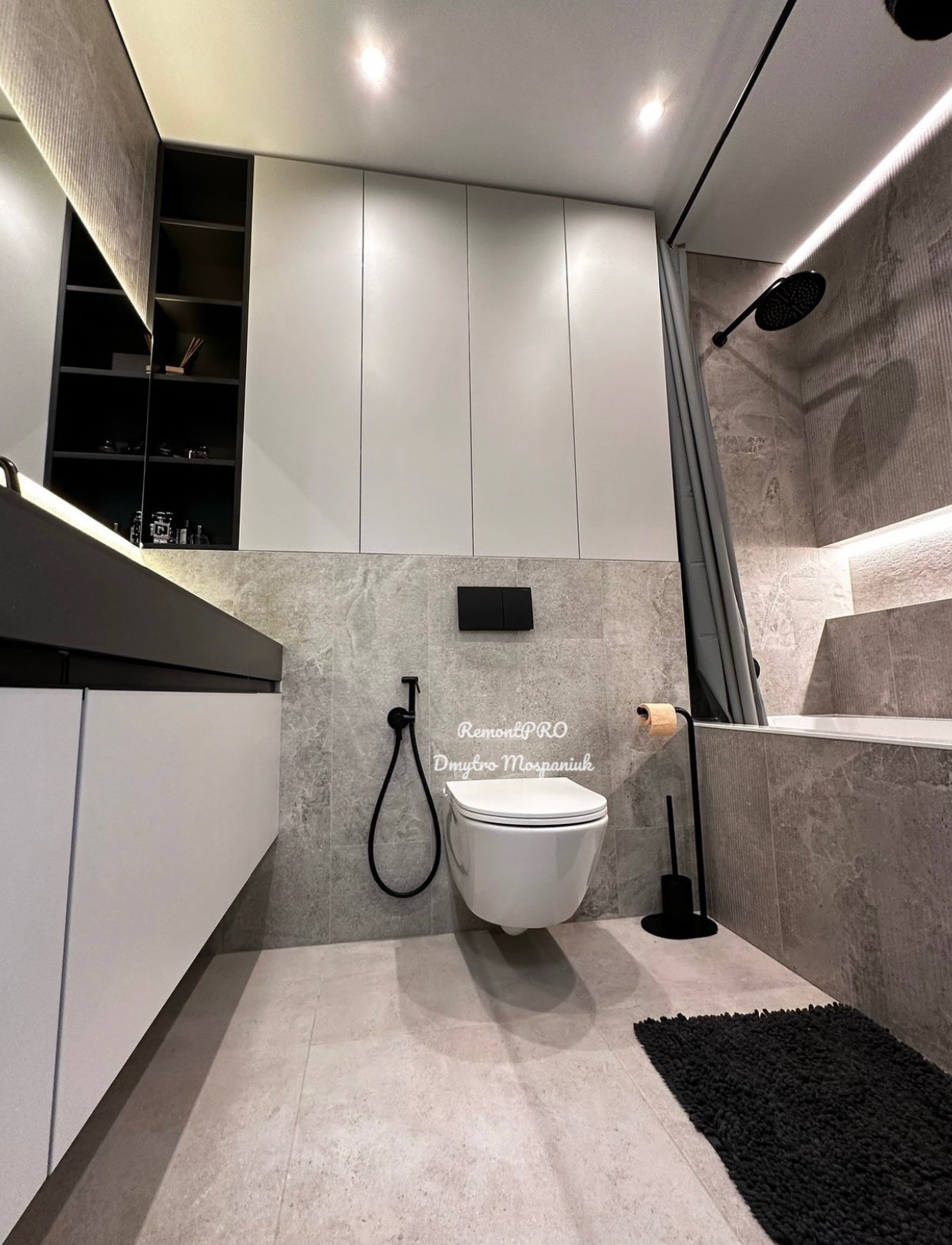 Nowoczesna łazienka w szarościach z podwieszaną toaletą, czarną armaturą i oświetleniem LED.