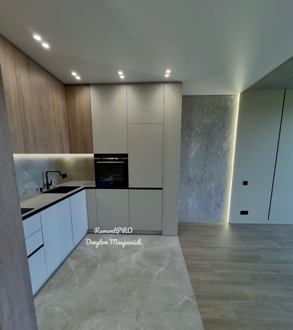 Nowoczesna kuchnia z szarymi płytkami podłogowymi imitującymi marmur, jasnymi szafkami i drewnopodobnymi frontami, czarnym zlewem i minimalistyczną baterią oraz oświetleniem LED.