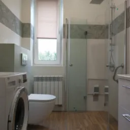 Nowoczesna łazienka w Krakowie z kabiną prysznicową typu walk-in, umywalką z szafką, toaletą podwieszaną, pralką Beko i grzejnikiem drabinkowym, wykończona płytkami z motywem liści na pasie...