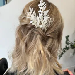 Upięcie blond włosów do ramion z wpiętą białą, delikatną ozdobą z suszonych roślin, widok z tyłu, naturalne światło.