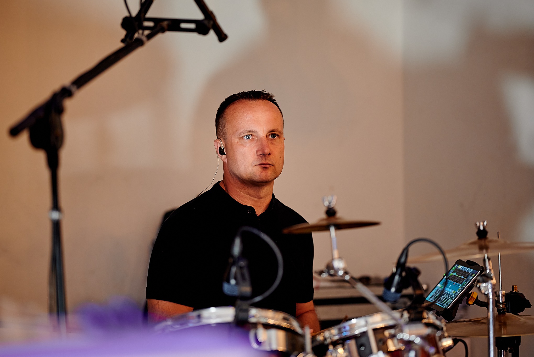 Perkusista z słuchawkami dousznymi podczas występu w Strzyżewicach, widoczny smartfon z aplikacją do miksowania dźwięku zamontowany na zestawie perkusyjnym.