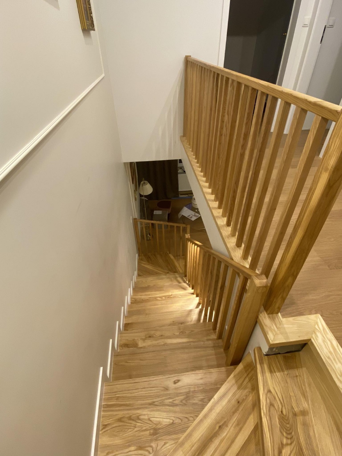 Drewniane schody z jasną balustradą, widok z góry. Naturalne wykończenie drewna i proste, nowoczesne wzornictwo. Element wystroju wnętrza.