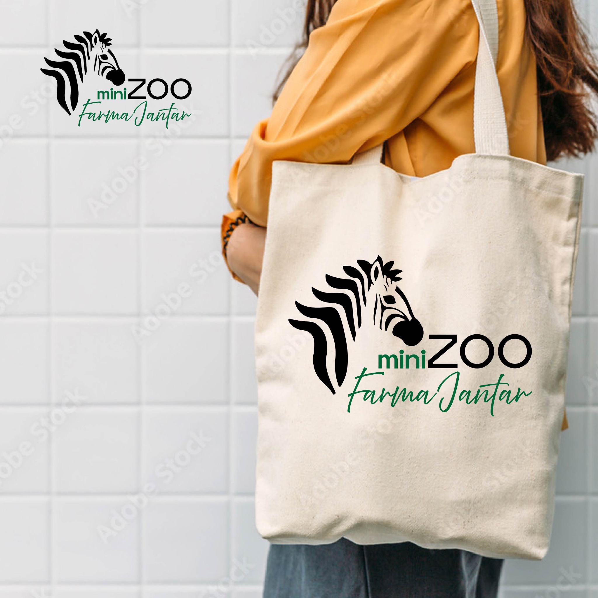 Bawełniana torba z nadrukowanym logo MiniZoo Farma Jantar, prezentowana przez osobę w żółtej bluzce na tle białych płytek.