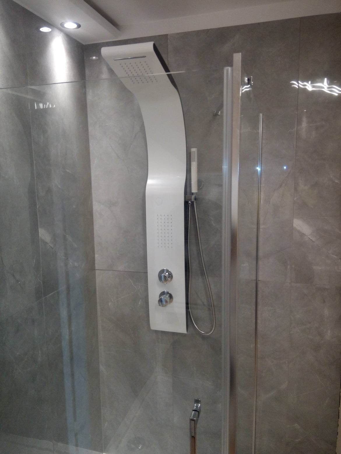 Nowoczesna kabina prysznicowa z panelem natryskowym w odcieniach szarości, z widocznymi chromowanymi elementami.