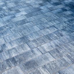 Hubert - Ułożona, szaro-niebieska kostka brukowa w kształcie prostokątów, ułożona pod kątem, z widoczną fakturą i drobnymi szczelinami wypełnionymi piaskiem.