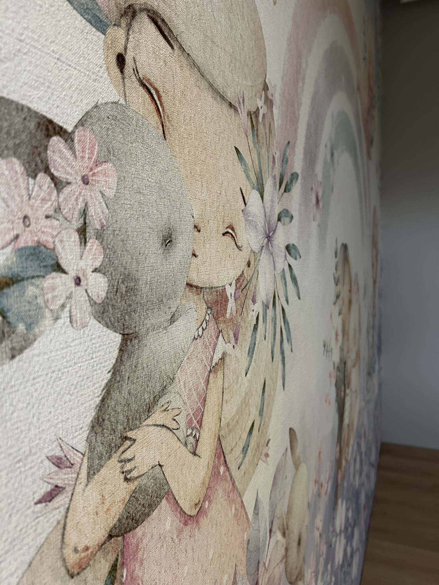 Dziecięca tapeta z motywem misia przytulającego dziewczynkę na tle tęczy i kwiatów, widoczna faktura tapety.