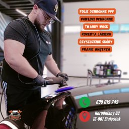 GHOST AUTODETAILING BIAŁYSTOK - Detailingowiec w czarnych rękawicach poleruje lakier samochodu, używając polerki Rupes, w tle widoczny wózek z kosmetykami samochodowymi.