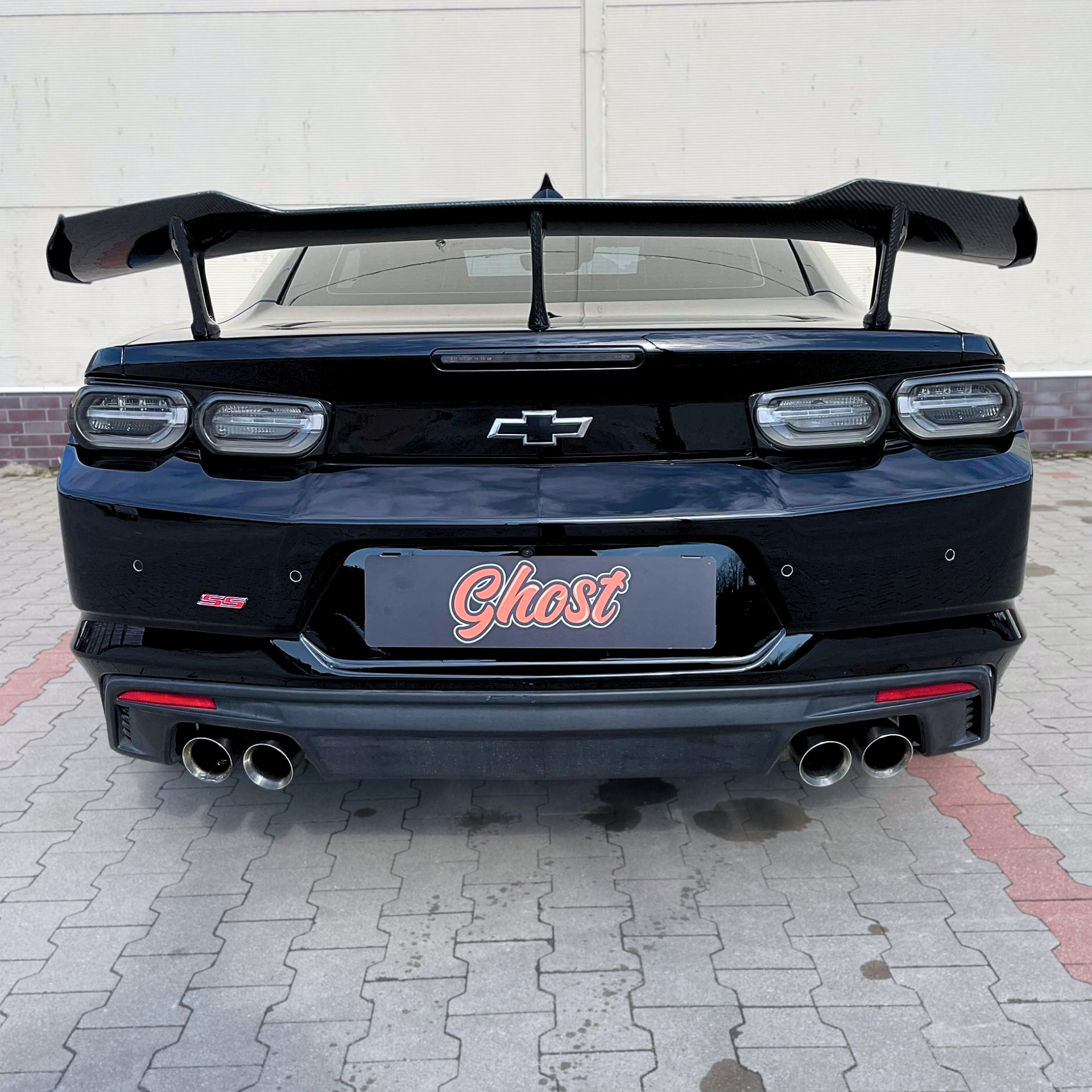 Czarny Chevrolet Camaro z dużym karbonowym spojlerem, widok z tyłu, na tablicy rejestracyjnej logo firmy detailingowej Ghost Autodetailing Białystok.