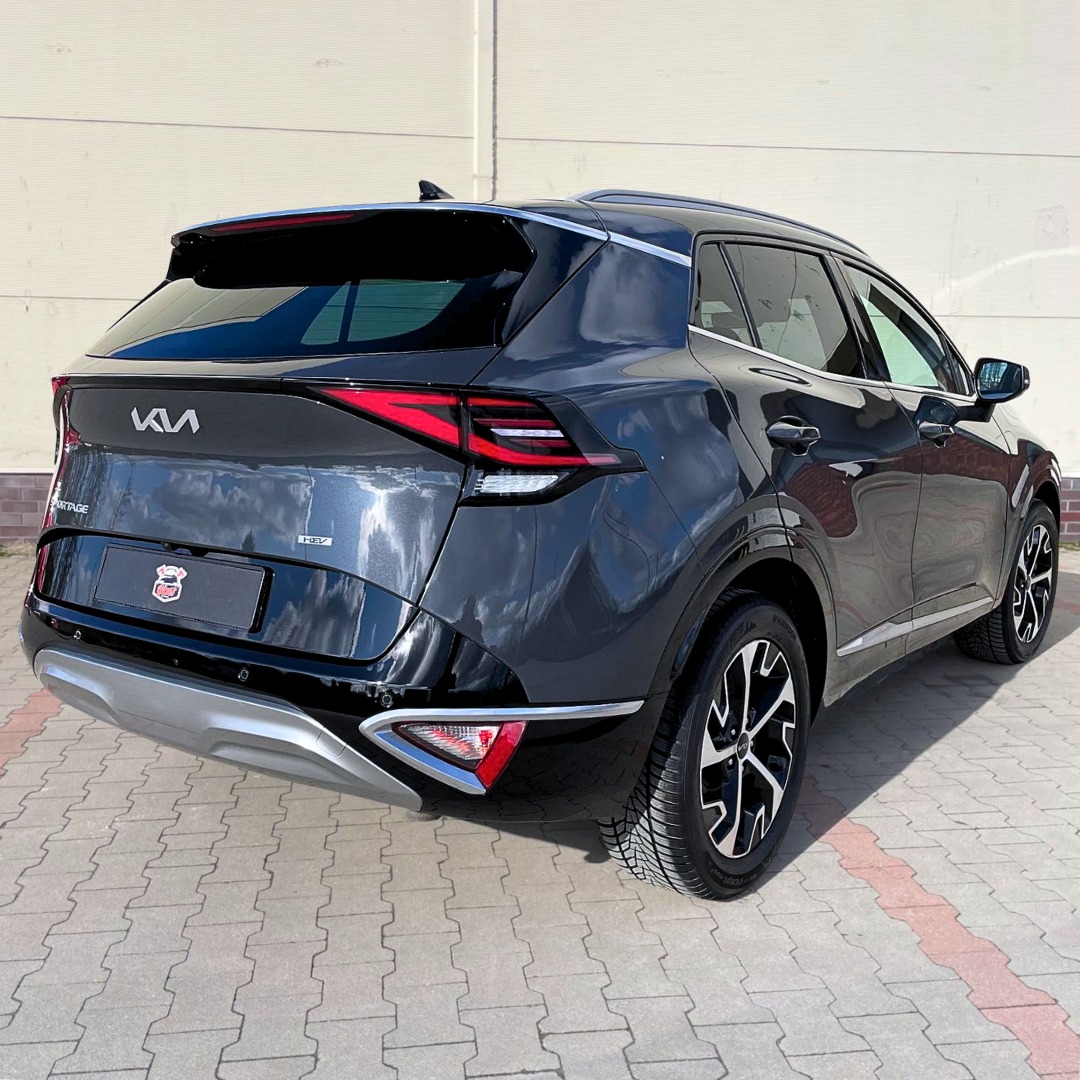 Błyszczący, czarny SUV Kia Sportage po zabiegach detailingowych, widoczny z tyłu, z wyraźnym odbiciem nieba w lakierze i czystymi felgami, zaparkowany na kostce brukowej.