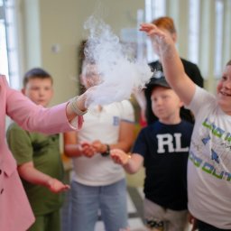 Baju Baj Animacje Organizacja Imprez - Animator w różowym żakiecie prezentuje dzieciom efektowny pokaz z dymem, wywołując uśmiechy i zaciekawienie podczas imprezy.