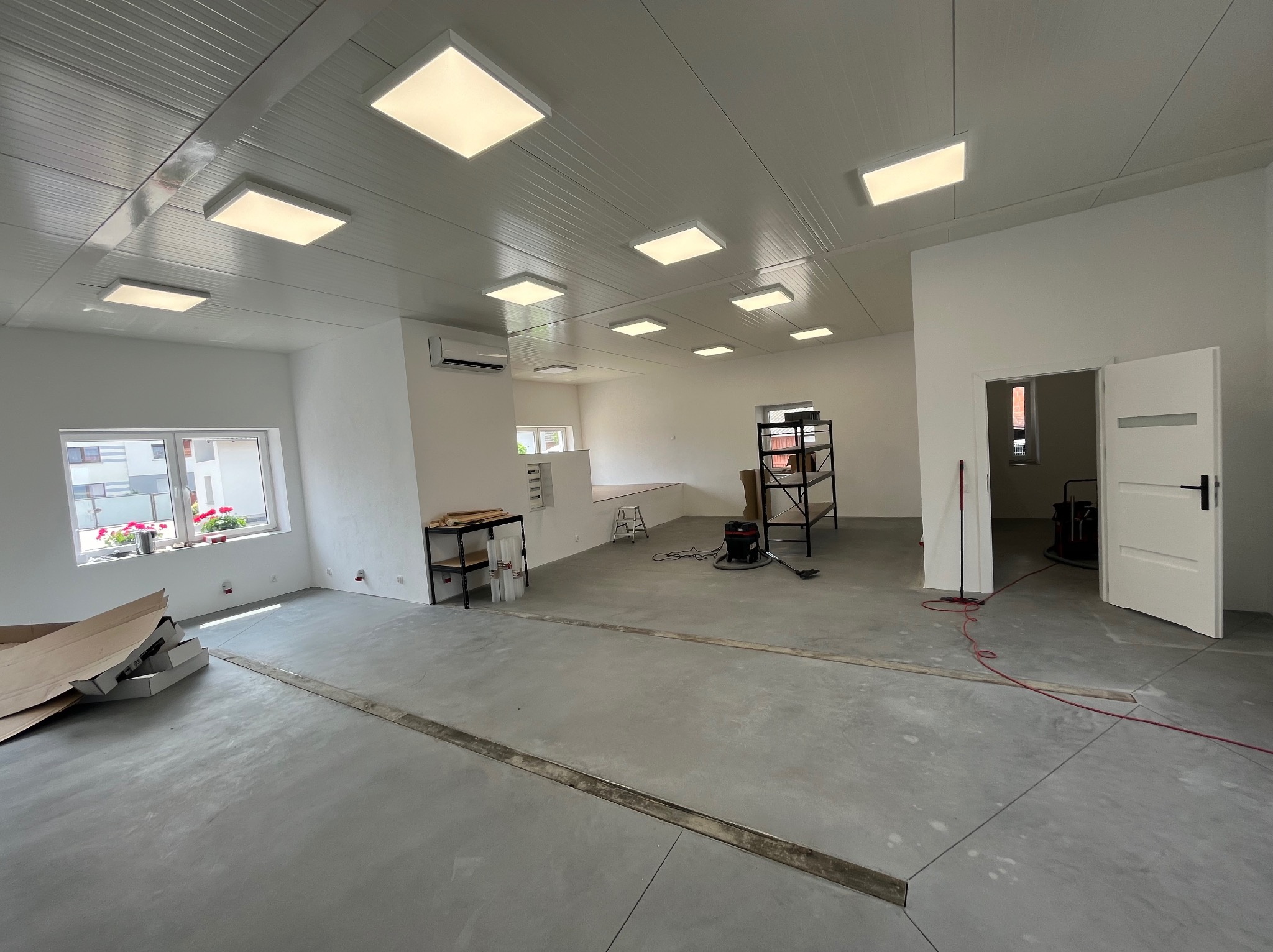 Wnętrze nowo wykończonego pomieszczenia w Szkaradowie z zamontowanym oświetleniem sufitowym LED, widoczne przygotowania do dalszych prac wykończeniowych.