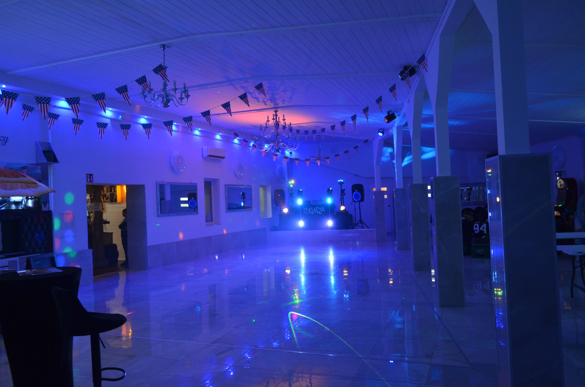 Sala bankietowa z klimatyzacją, oświetleniem dyskotekowym i dekoracjami w postaci flag USA. Widoczny klimatyzator na ścianie.