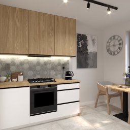 ENMAG.DESIGN Natalia Magiera - Jasna kuchnia z drewnianymi szafkami górnymi, białymi dolnymi, mozaiką na ścianie, czarnym piekarnikiem, płytą grzewczą i czajnikiem elektrycznym, stół z krzesłami przy oknie, dekoracje.