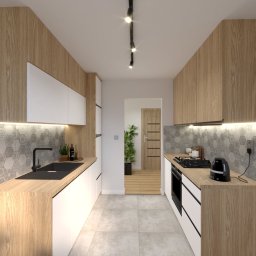 ENMAG.DESIGN Natalia Magiera - Wąska kuchnia z drewnianymi i białymi szafkami, heksagonalnymi płytkami na ścianie, czarnym zlewem i czajnikiem, oświetleniem punktowym i widokiem na przedpokój z rośliną doniczkową.