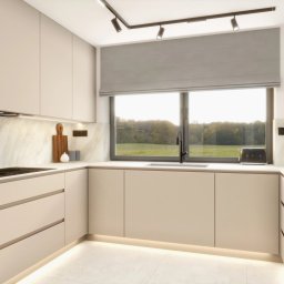 ENMAG.DESIGN Natalia Magiera - Jasna, minimalistyczna kuchnia z beżowymi frontami szafek, marmurowym blatem i subtelnym oświetleniem LED pod szafkami, widok na zieleń za oknem.