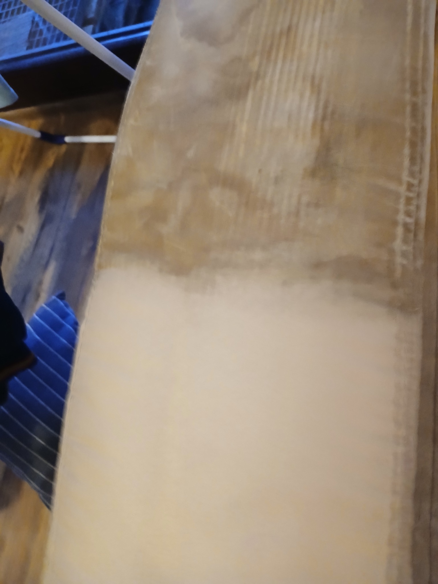 Fragment dywanu z widocznym efektem czyszczenia: górna część zabrudzona, dolna - wyczyszczona, obok widoczny fragment niebieskiej tkaniny.