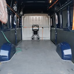 Usługi Trans Janusz Kaczorowski - Wnętrze pustego, przygotowanego do transportu busa w kolorze granatowym, widok z tyłu. Widoczne zabezpieczenia ładunku i czysta podłoga.