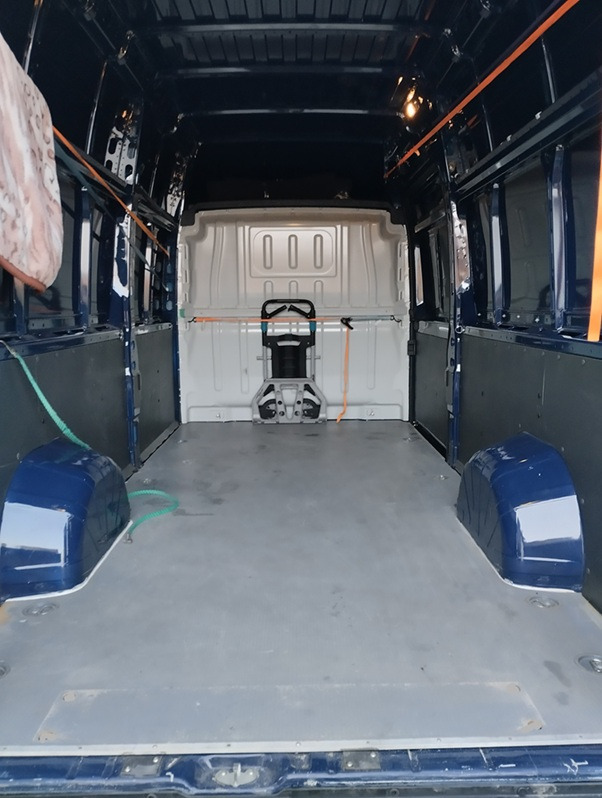 Wnętrze pustego, przygotowanego do transportu busa z zabezpieczeniami ładunku i zamontowanym wózkiem transportowym, gotowe do załadunku i przewozu.