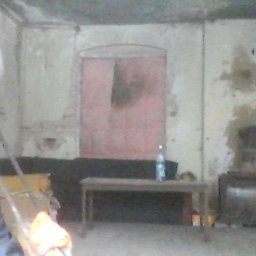 nie mam firmy - Wnętrze remontowanego pomieszczenia z widocznymi śladami po pracach na ścianach, z centralnie umieszczonym otworem drzwiowym pomalowanym na różowo, z widocznymi meblami i butelką wody na stole...