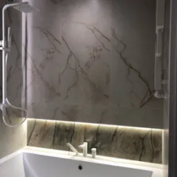 Biała wanna z baterią i odpływem, podświetlona listwą LED, z marmurowymi płytkami na ścianach i deszczownicą.