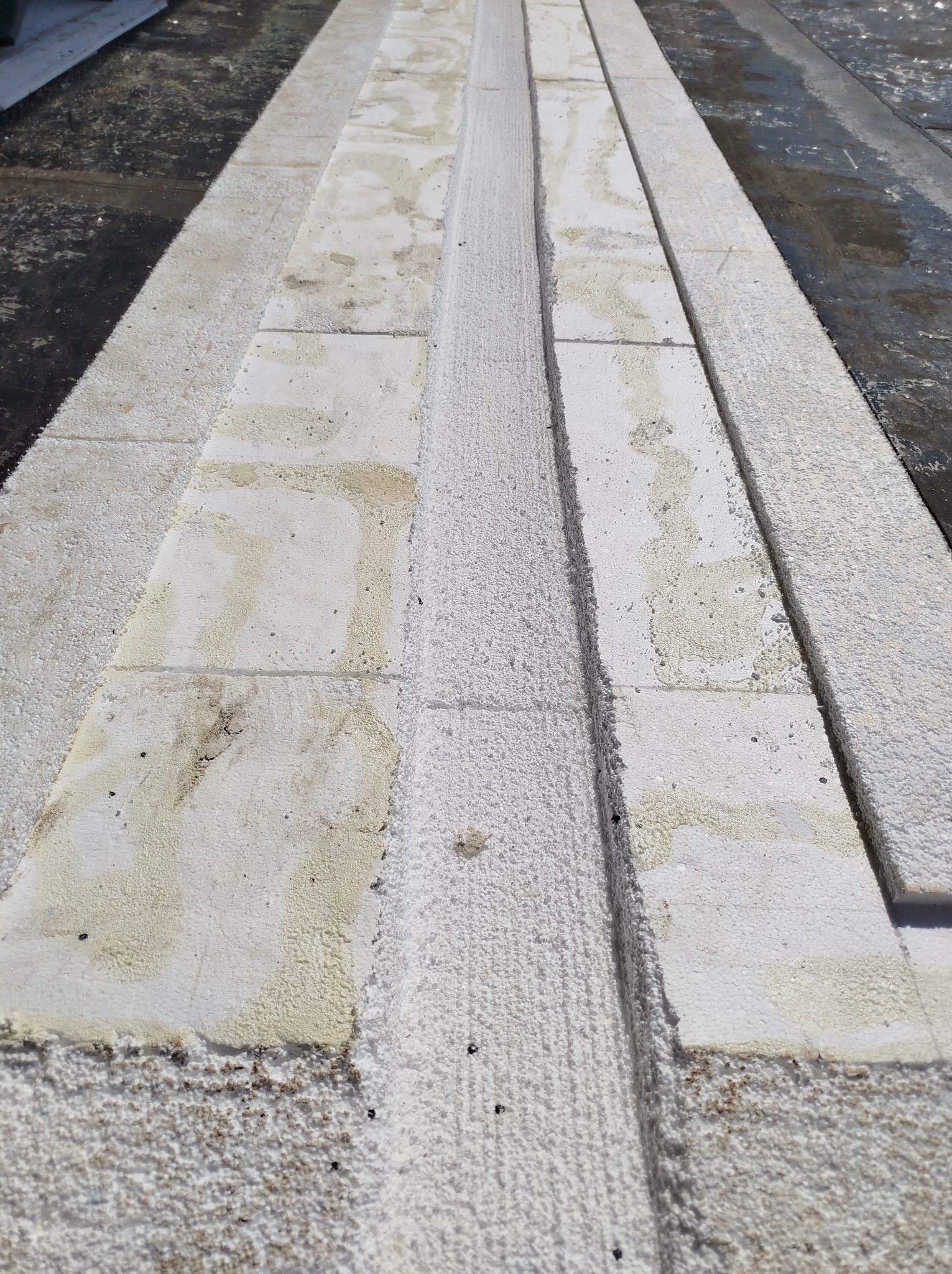 Ocieplenie dachu wełną mineralną, widok z bliska na warstwy izolacyjne i elementy konstrukcyjne dachu.