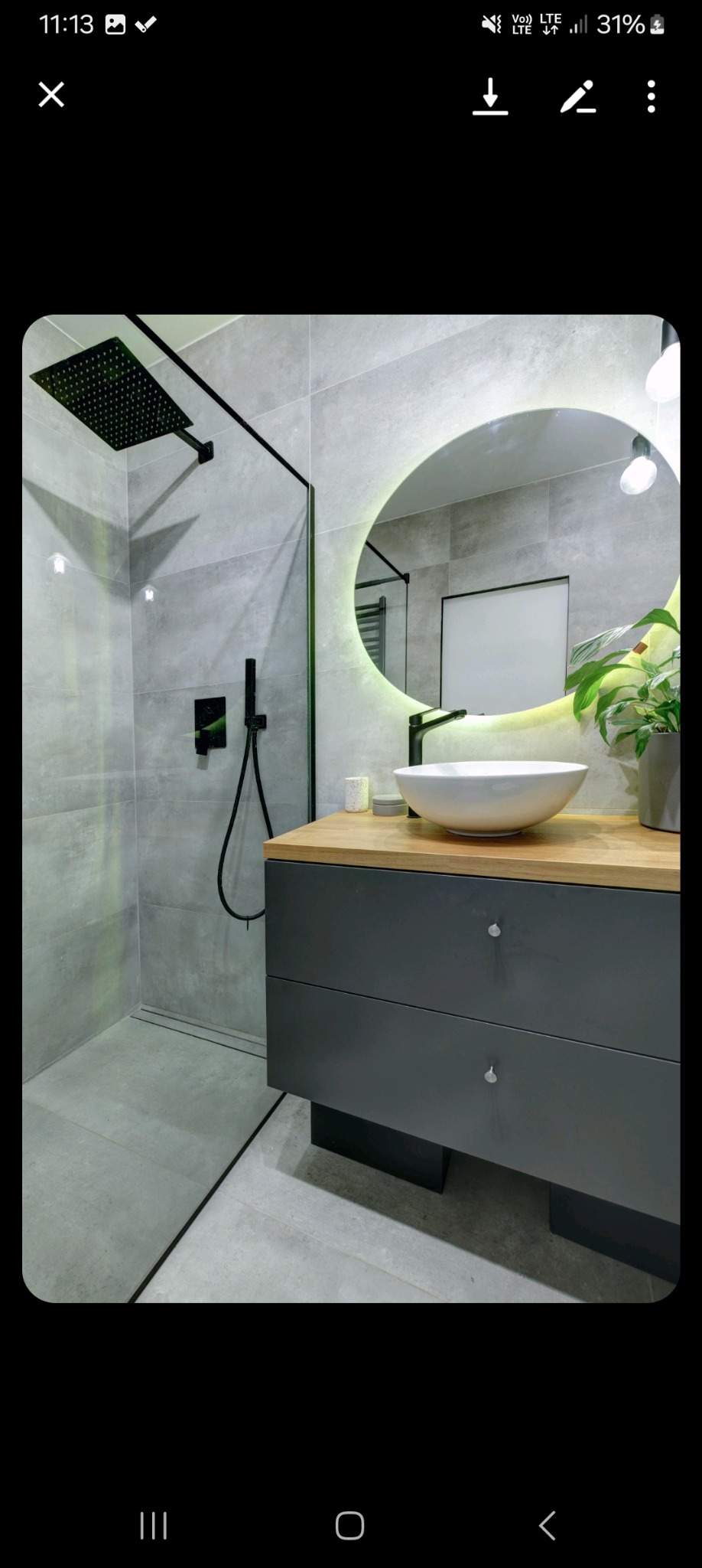 Nowoczesna łazienka w Lublinie z szarą płytką, kabiną prysznicową typu walk-in z czarną armaturą, okrągłym lustrem z podświetleniem LED i drewnianym blatem pod umywalką nablatową.